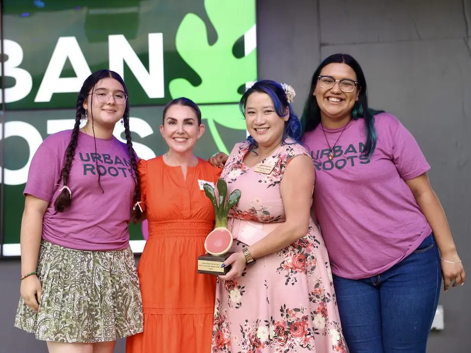 Four people pose with a radish shaped award at Tour de Farm, an Urban Roots fundraiser. Two youth, Amberly and Yoselyn, pose with Urban Roots board member Cat Duong and Audrey Garcia, an HEB representative.