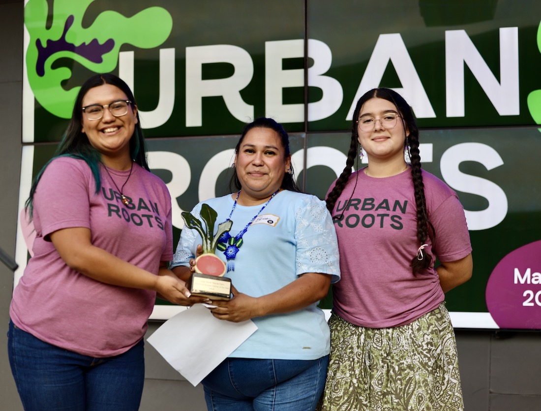 Two urban Roots youth, Yoselyn and Amberly, present an award to Erica at Tour de Farm, to Erica Reyes, who accepts it on behalf of Go Austin Vamos Austin.
